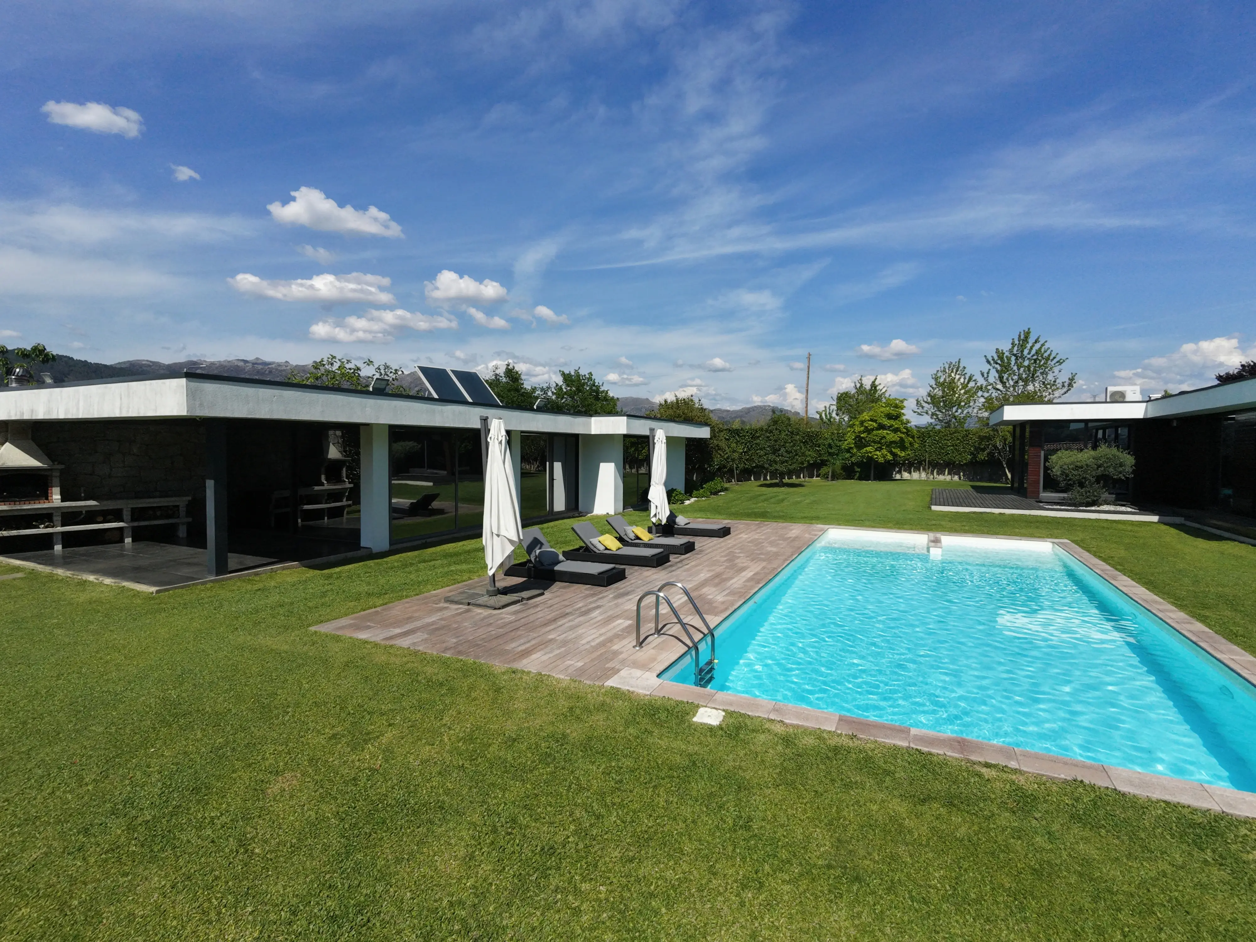 Solárium de la piscina con tumbonas y sombrilla