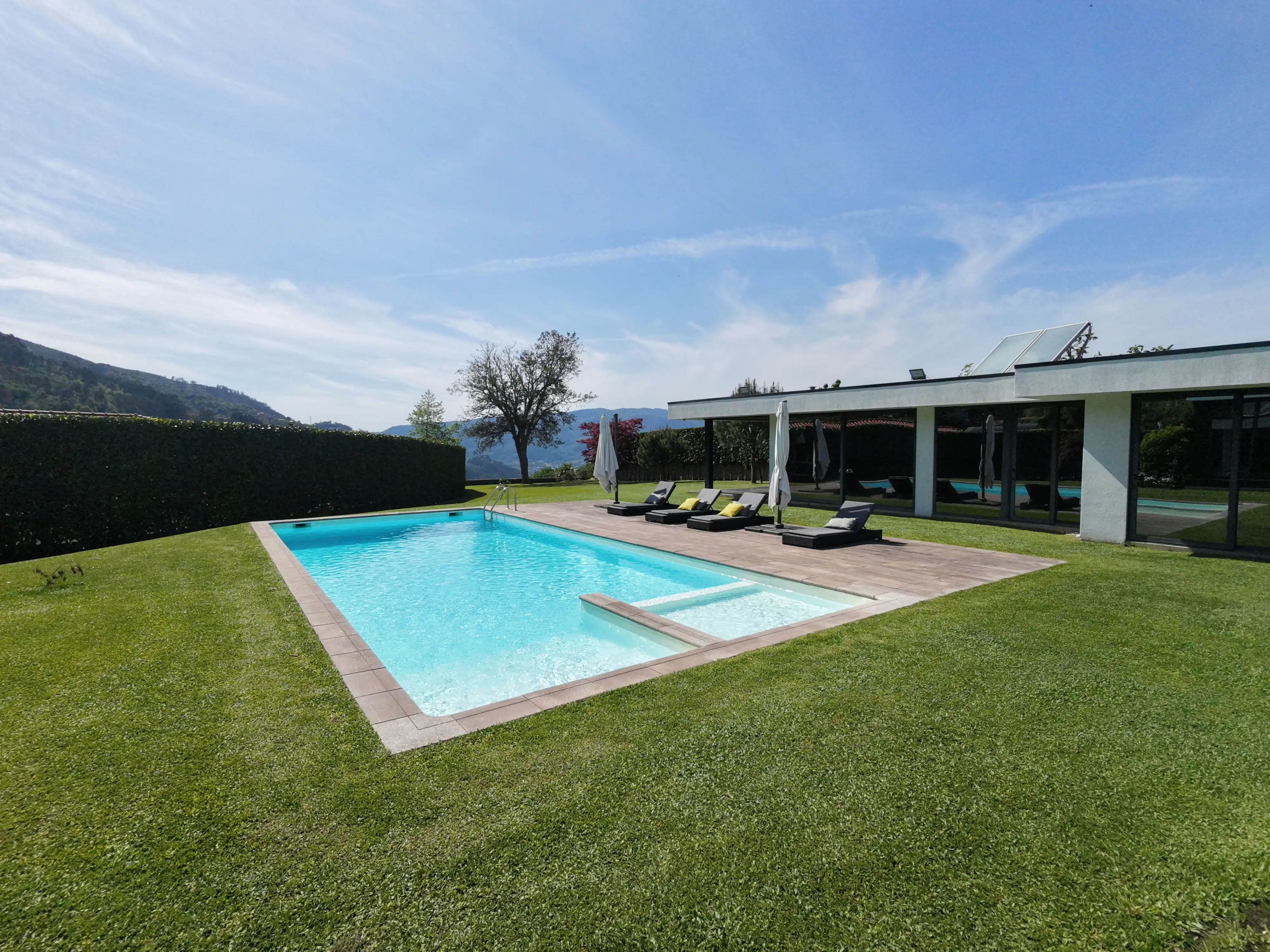 Piscina con tumbonas y terraza cubierta